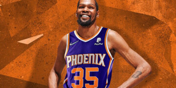 Kevin Durant poses in a Phoenix suns jersey in front of an orange background