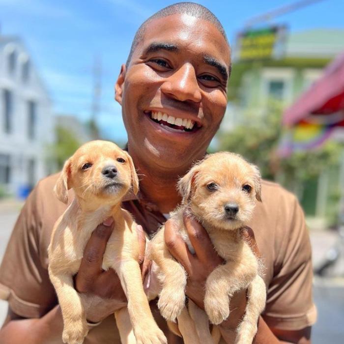 Jay poses to two adorable puppies