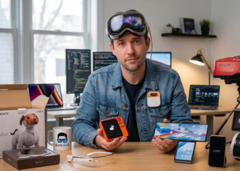 A man at a desk with failed tech products like Apple Vision Pro, Rabbit R1, and Amazon Astro for DorkDesk.