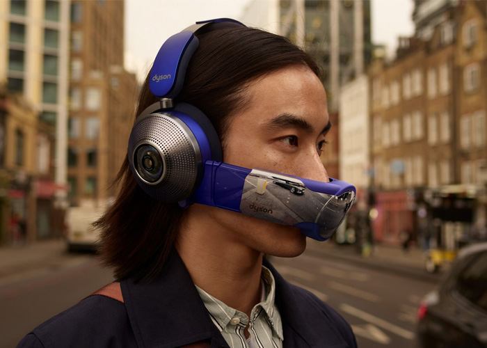 Person wearing blue Dyson Zone air-purifying headphones with a silver face visor on a city street.