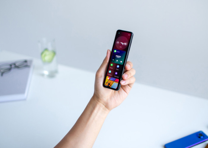 A person hold an Essential Phone project Gem with a white background and a book and glasses.