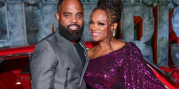 Todd Tucker wearing a grey blazer and Kandi Burruss wearing a sparkly purple sequin dress posing together in front of a classic red car.