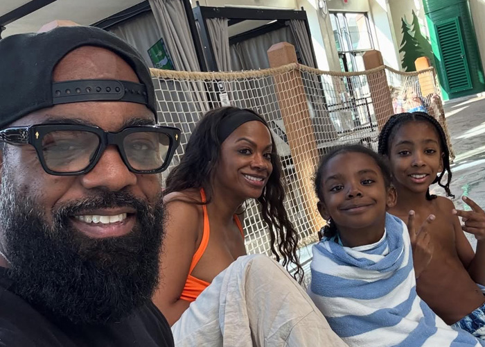 Todd Tuck and Kandi Burrus taking a happy selfie together while relaxing by the cabanas at a sunny indoor water park with their children.