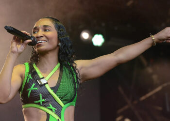 Rozonda Chilli Thomas of TLC performing live on stage in a neon green cyber-aesthetic outfit while singing