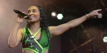 Rozonda Chilli Thomas of TLC performing live on stage in a neon green cyber-aesthetic outfit while singing