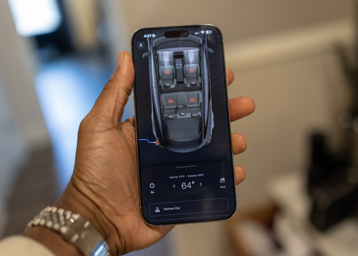 A iPhone 16 showing the Tesla app, it is open to a screen that shows a car's interior being warmed and the seats being warmed to prepare the care for a cold drive