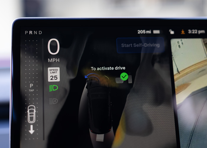 The Tesla center screen showing a 'D' or 'R' automatically highlighted based on the obstacles detected around the vehicle.